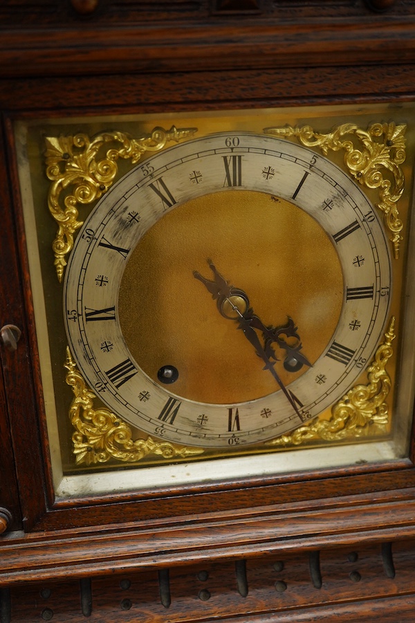 An early 20th century carved oak mantel clock, with key and pendulum, 58cm high